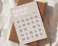 the bridal bingo game is sitting on top of two books, one brown and one white