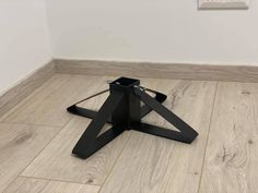 a black metal object sitting on top of a wooden floor next to a white wall