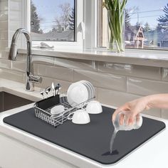 a person's hand is pouring water from a dishwasher into a sink