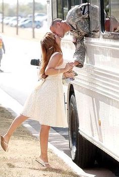 a man kissing a woman in front of a bus on the side of the road