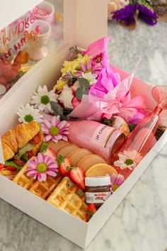 a white box filled with lots of different types of food and flowers on top of a table