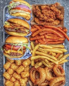 the tray is full of different types of burgers, fries and onion rings on it