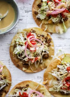 four tacos with toppings are on a table