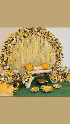 a decorated stage with sunflowers and other flowers on the side, surrounded by yellow pillows