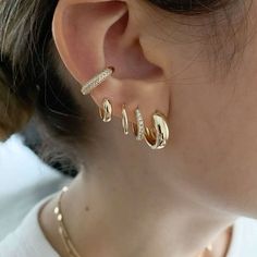 a close up of a person wearing gold ear rings and earrings with diamonds on them