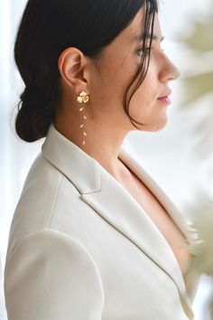 a woman in a white suit and gold earrings