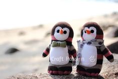 two stuffed penguins sitting on top of a rock