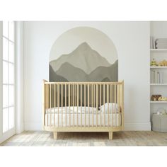 a baby crib with mountains painted on the wall