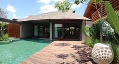 a house with a pool in the middle of it and a wooden deck next to it