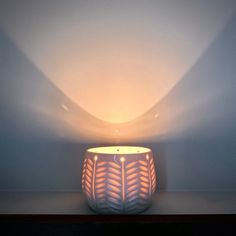 a white lamp sitting on top of a wooden table next to a light blue wall