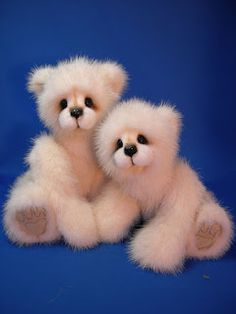 two white teddy bears sitting next to each other on a blue background with one bear holding the other