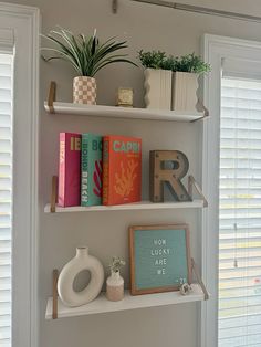 two white shelves with books and plants on them