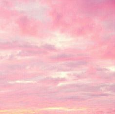 an airplane is flying in the sky with pink and yellow clouds above it at sunset