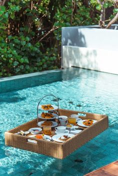 a wicker tray filled with food sitting on top of a swimming pool