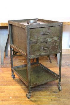 an old metal filing cabinet on wheels with two drawers and one drawer open, sitting on a hard wood floor