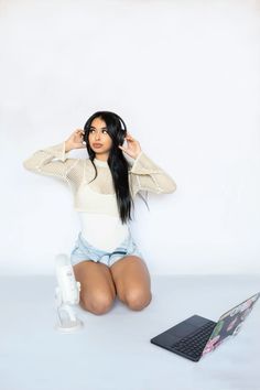 a woman sitting on the ground with her hands behind her head and laptop in front of her