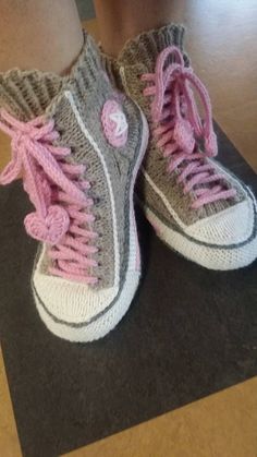 a pair of shoes with pink laces on the bottom and gray soles, sitting on top of a black mat