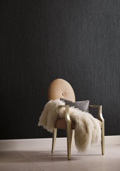 a chair that has some fur on it and is next to a wall with a black background