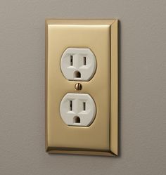 an electrical outlet on the wall with two outlets and one light switch in gold plated metal