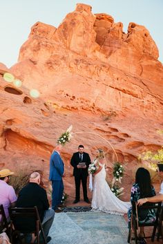 a bride and groom are getting married in front of the red rock formations at sunset