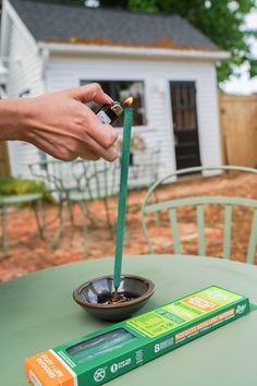 a person holding an electronic device over a bowl on top of a green table outside