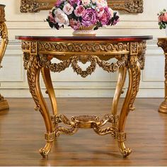 an ornately decorated table with vases and flowers on it in front of a painting