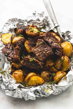 steak and potatoes in foil with herbs on top, ready to be eaten or served