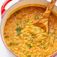 a red pot filled with soup and a wooden spoon