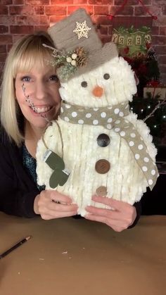 a woman holding up a snowman made out of sweaters