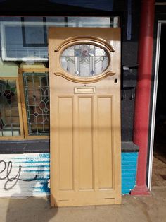 a wooden door with a clock on the front and side of it in front of a store