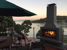 a man sitting in front of an outdoor fireplace