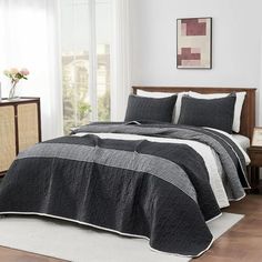 a bed with black and white bedspread in a room next to a window