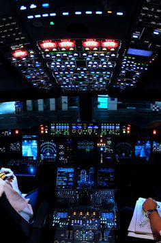 two pilots are sitting in the cockpit of an airplane at night with their lights on