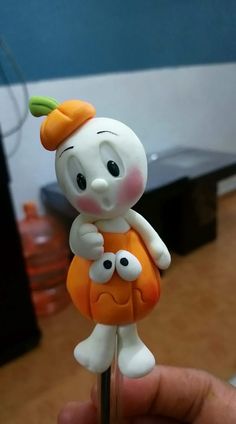 a person holding a small toy with an orange outfit on it's head and eyes