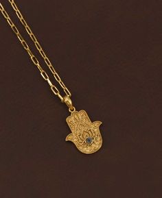 Explore the fusion of spiritual symbolism and artistic design with the 18K gold plated brass necklace, featuring an exquisitely crafted hamsa hand pendant. This ancient symbol, renowned for its protective qualities, is intricately embossed, showcasing a level of craftsmanship that brings depth and texture to the design. Adding to its allure, the pendant is adorned with a small, elegantly studded gemstone, available in three captivating options: the tranquil Amethyst, the mystical Labradorite, an Spiritual Gold-plated Necklaces With Intricate Design, Spiritual Gold Plated Necklaces With Intricate Design, Spiritual Gold Plated Necklace With Intricate Design, Handmade Gold Star Of David Necklace, Gold Evil Eye Jewelry For Blessing, Gold Star Of David Amulet Necklace, Traditional Gold Evil Eye Necklace, Handmade Spiritual Gold-plated Charm Necklaces, Hamsa Hand Necklace