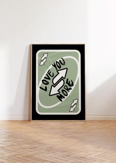 a black and green poster with the words love you more on it in front of a white wall