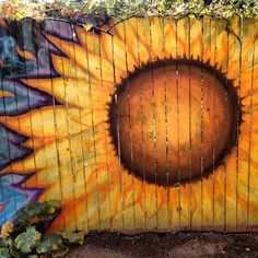 a wooden fence painted with a sunflower and the words happy day written on it