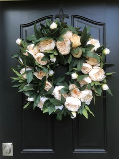 a wreath with white flowers on a black door