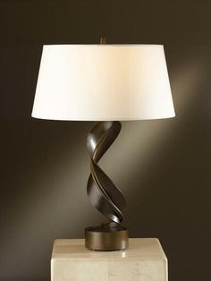 a lamp that is sitting on top of a table with a white shade over it