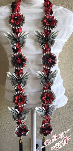 a white mannequin with red and silver flowers on it's neckline