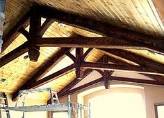 a loft with wooden beams and ladders on the ceiling is being worked on by an expert