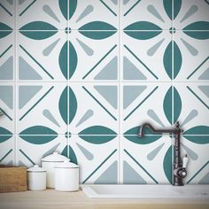 a kitchen with green and white tiles on the wall next to a faucet