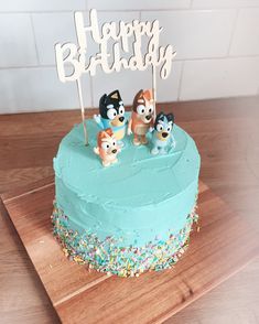 a birthday cake decorated with three dogs and the words happy birthday on top is blue frosting