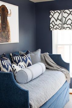 a living room with blue walls and couches in front of a window that has an animal painting on the wall