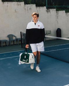 a man holding a tennis bag on top of a tennis court