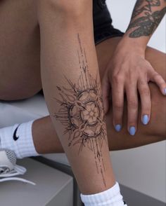 a woman's leg with a tattoo on it and her hand resting on the ground