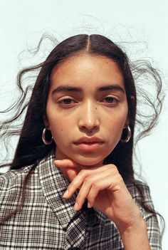 a young woman with long hair is looking at the camera and has her hand on her chin