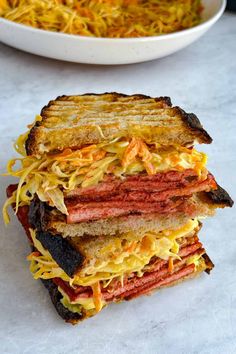 two sandwiches stacked on top of each other in front of a bowl of spaghetti noodles