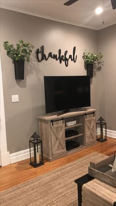 a living room with a large tv on the wall and two planters above it