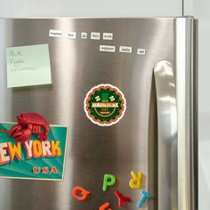 magnets and stickers on the side of a refrigerator freezer with new york written on it